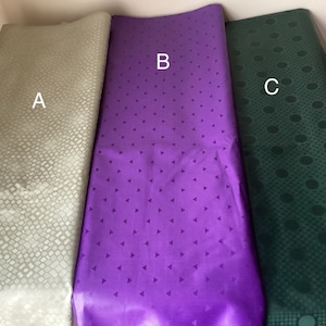 May include: Three fabric swatches with different patterns. The swatch labeled "A" has a light green, textured pattern. The swatch labeled "B" has a purple background with a white triangle pattern. The swatch labeled "C" has a dark green background with a white circle pattern.