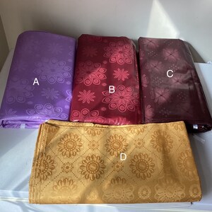 May include: Four folded fabric pieces in shades of purple, red, and gold. Each piece features a floral pattern. The fabrics are labeled A, B, C, and D. The fabrics are likely used for clothing or home decor.