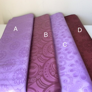 May include: Four different fabric swatches with various patterns. The swatches are labeled A, B, C, and D. The fabric is a light purple color with a floral pattern. The fabric is a dark purple color with a paisley pattern. The fabric is a light purple color with a floral pattern. The fabric is a dark red color with a floral pattern.