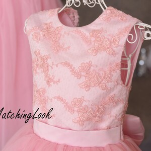 Puede incluir: Un vestido de tul rosa con un corpi&ntilde;o de encaje rosa y una cinta rosa a juego. El vestido tiene un escote redondo y es sin mangas. El texto "MatchingLook" es visible en el vestido.