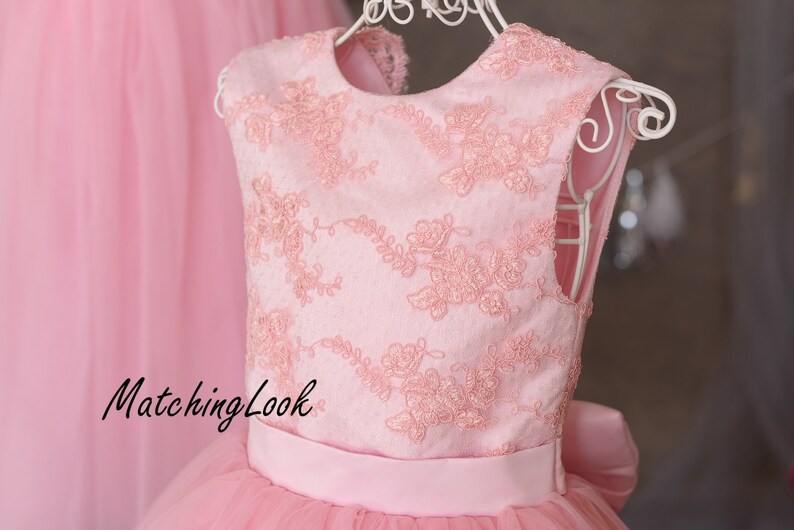 Puede incluir: Un vestido de tul rosa con un corpi&ntilde;o de encaje rosa y una cinta rosa a juego. El vestido tiene un escote redondo y es sin mangas. El texto "MatchingLook" es visible en el vestido.
