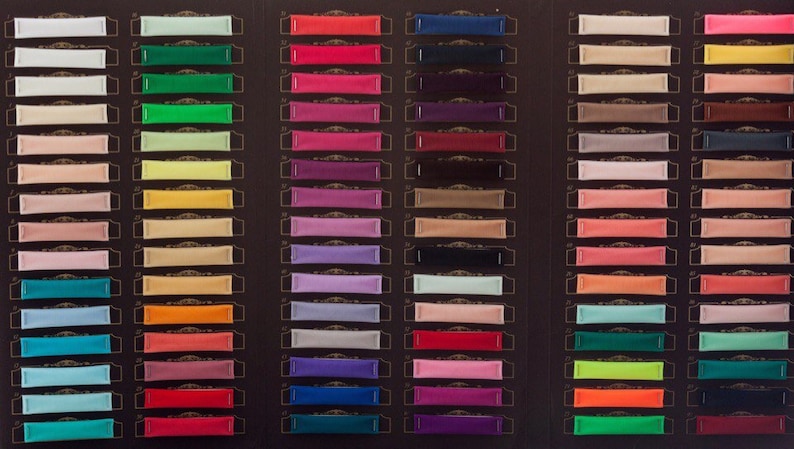 Pu&ograve; includere: Una cartella colori con 18 righe di campioni di tessuto. Ogni riga ha 5 campioni di tessuto in diversi colori. I colori includono bianco, verde, rosso, nero e beige.