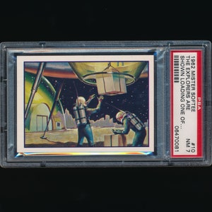 May include: A vintage trading card featuring a colorful illustration of two astronauts loading cargo into a spaceship. The card is graded NM 7 by PSA and has the number 10 printed on it. The text on the card reads "1962 Mister Softee The Explorers are shown loading one of... 06470081".