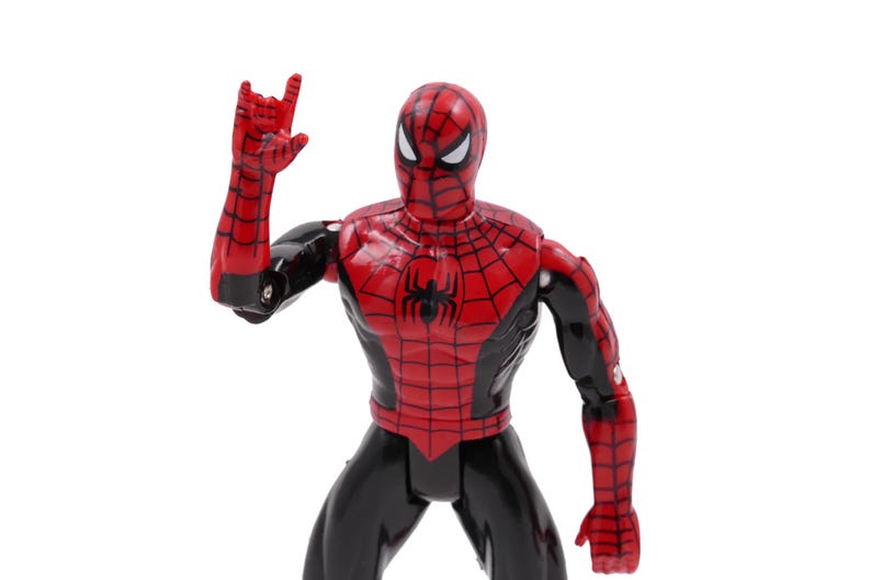May include: A red and black Spider-Man action figure with a web design on the chest and arms. The figure is posed with one arm raised, hand in a gesture. The figure is on a white background.