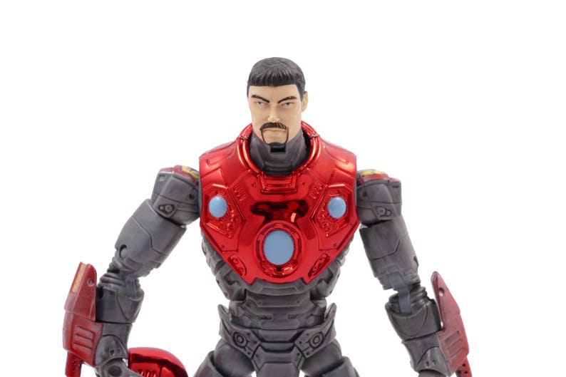 Op de afbeelding: Gedetailleerd actiefiguur van een man in een rood en grijs pantserpak. Het figuur heeft een metallic rode borstplaat met blauwe accenten en een gedetailleerd gezicht met een snor. De armen en benen zijn grijs met rode details.