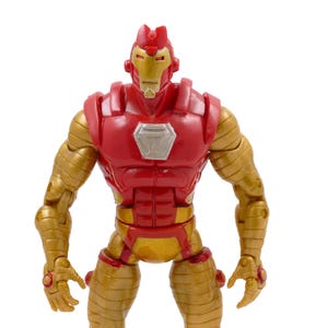 May include: A red and gold Iron Man action figure. The figure has a red torso and head with gold arms, legs, and accents. The figure has a silver chest plate and is standing upright.