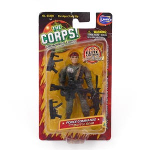 May include: The Corps! Commando Force action figure in original packaging. The figure wears a red beret and camouflage uniform, holding a black rifle. Accessories include two additional black firearms. The card features text: The Corps! Elite Edition.