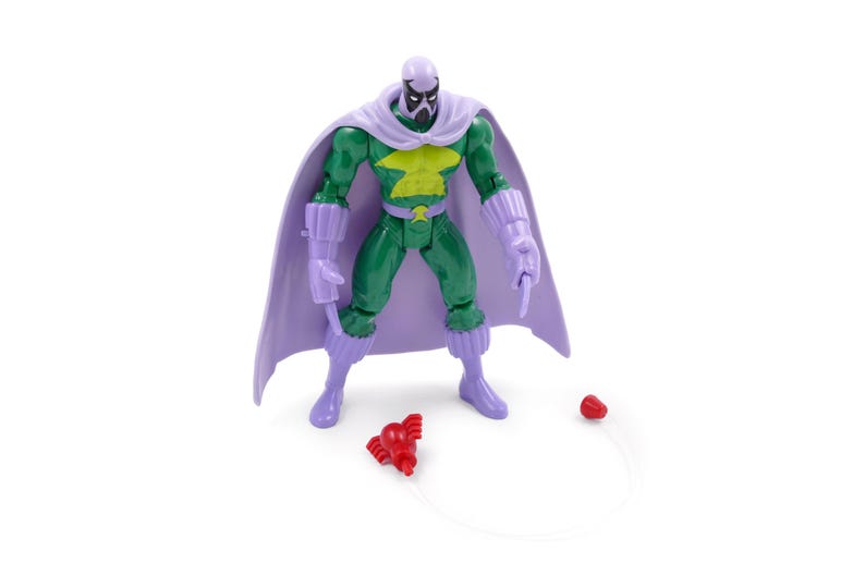 Puede incluir: Una figura de acci&oacute;n verde con capa, guantes y botas moradas. La figura tiene un emblema amarillo en el pecho y una m&aacute;scara morada. Un accesorio rojo est&aacute; en el suelo, conectado por una cuerda.