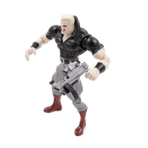 May include: Action figure of a muscular character with a pale complexion, wearing a black top, gray pants, and brown boots. The figure is holding a gray weapon and has black wristbands. The figure has a determined expression.