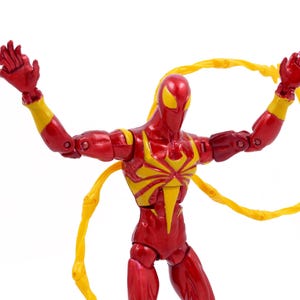 May include: Red and yellow action figure of a superhero with web-like appendages. The figure is posed with arms raised and web-like appendages extended.