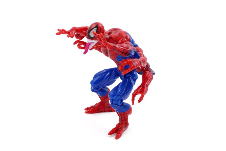 May include: A red, blue, and white action figure of a superhero with a white-eyed mask, a long pink tongue, and a muscular build. The figure is in a crouching pose, with its arms outstretched.