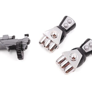 May include: A gray toy machine gun with a black ammunition belt and two black and silver robotic fists. The toy gun has a scope and a handle. The fists have silver knuckles and black cuffs.