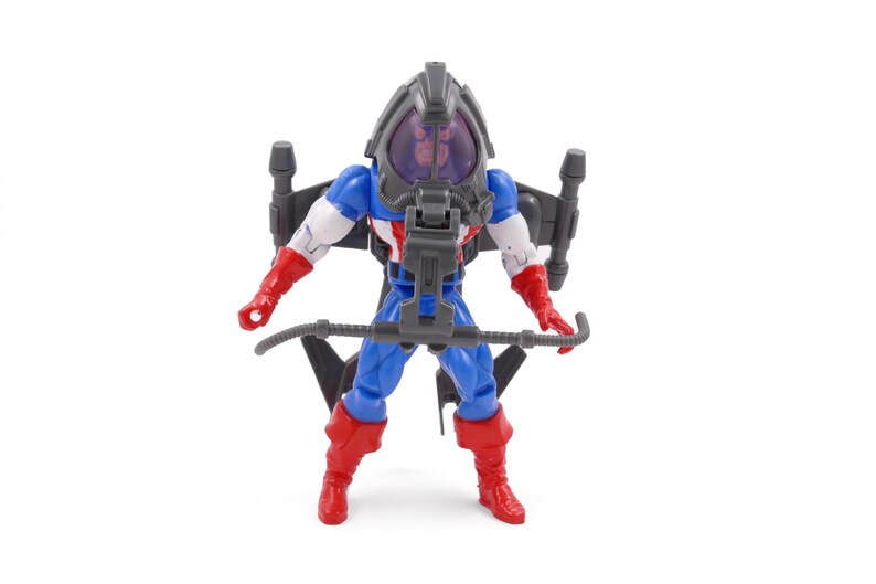 Pode incluir: Figura de a&ccedil;&atilde;o do Capit&atilde;o Am&eacute;rica com um jetpack e um capacete. A figura est&aacute; vestida com um traje azul, branco e vermelho com luvas e botas vermelhas. O jetpack &eacute; preto e cinza, e o capacete tem uma viseira transparente.