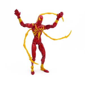 May include: Red and yellow action figure of a superhero with long, yellow, web-like appendages. The figure is posed with arms raised and legs spread.