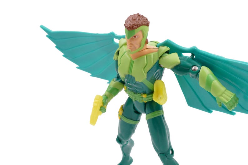 May include: Action figure of a superhero with green and blue wings. The figure is wearing a green and blue suit with yellow accents. The figure is holding a yellow weapon. The figure has brown hair and a green helmet.