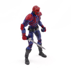 May include: A Red Skull action figure, featuring a red skull head, red and blue armor, and a silver sword. The figure is posed against a white background, showcasing its detailed design and menacing appearance. The figure is approximately 6 inches tall.