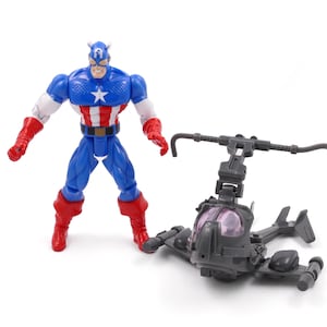 Pode incluir: Uma figura de a&ccedil;&atilde;o do Capit&atilde;o Am&eacute;rica em um traje cl&aacute;ssico azul, branco e vermelho est&aacute; ao lado de um helic&oacute;ptero de brinquedo cinza. A figura tem uma estrela no peito e um capacete. O helic&oacute;ptero tem um cockpit transparente.