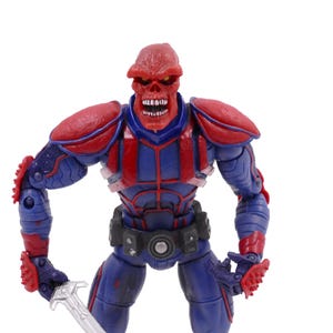 May include: A Red Skull action figure, a Marvel Comics supervillain, stands with a sword. The figure is predominantly blue and red, with a skull-like head and detailed armor. The figure is posed against a white background.