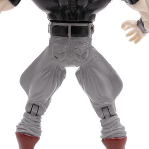 May include: A detailed view of a toy action figure, showcasing the lower torso and legs. The figure wears gray pants with a black belt and a black top. The figure's hands are visible, and the boots are red.