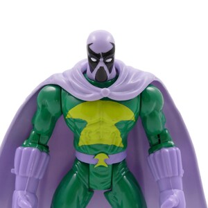 Puede incluir: Figura de acci&oacute;n verde con un emblema de pecho amarillo, capa morada y guantes a juego. La figura tiene una cara enmascarada con una cabeza morada y una m&aacute;scara negra. La figura es un superh&eacute;roe o un villano.