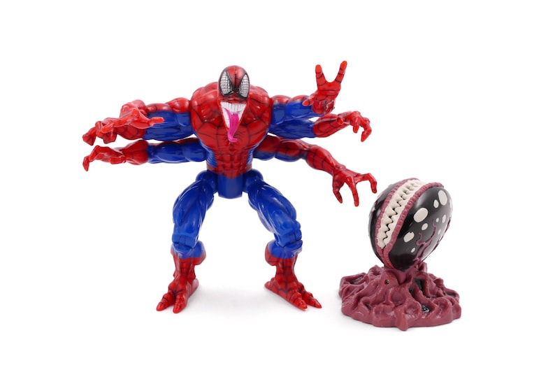 May include: A Spider-Man action figure with multiple arms, red and blue suit, and a long pink tongue. Beside it is a black and white creature with a toothy grin, on a maroon base. A collectible toy.