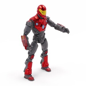 Op de afbeelding: Een rood en grijs actiefiguur van een superheld met een helm en harnas. Het figuur heeft een rode helm met een gele vizier, rode borstpantsering en rode accenten op de benen en armen. Het figuur staat met &eacute;&eacute;n arm uitgestrekt.