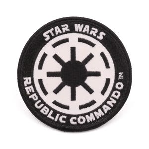 May include: Circular patch featuring the Star Wars Republic Commando logo. The patch has a black border with white text that reads "STAR WARS" at the top and "REPUBLIC COMMANDO" at the bottom. The central design is a white symbol on a black background.