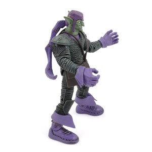 K&ouml;nnte beinhalten: Eine Green Goblin Actionfigur mit lila Hut, Handschuhen und Stiefeln. Die Figur hat ein finsteres Grinsen und tr&auml;gt ein dunkelgraues Outfit mit strukturiertem Design. Die Figur ist mit ausgestreckten Armen dargestellt.