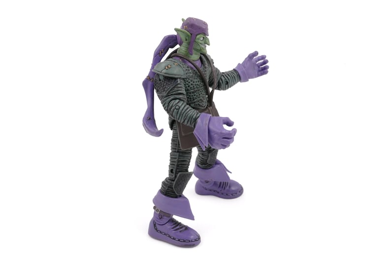 K&ouml;nnte beinhalten: Eine Green Goblin Actionfigur mit lila Hut, Handschuhen und Stiefeln. Die Figur hat ein finsteres Grinsen und tr&auml;gt ein dunkelgraues Outfit mit strukturiertem Design. Die Figur ist mit ausgestreckten Armen dargestellt.