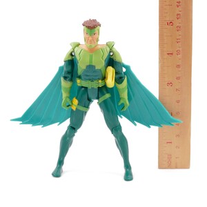 May include: A green and teal action figure of a superhero with a brown hairstyle and teal wings. The figure is wearing a green and teal suit with a yellow belt. A wooden ruler is next to the figure, measuring approximately 5 inches.