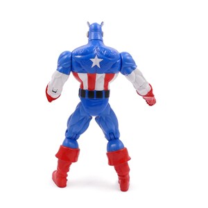 Pode incluir: Figura de a&ccedil;&atilde;o do Capit&atilde;o Am&eacute;rica azul, vermelho e branco, vista de tr&aacute;s. A figura tem um capacete azul, bra&ccedil;os brancos e botas vermelhas. As costas apresentam uma estrela branca sobre fundo azul e listras vermelhas e brancas.
