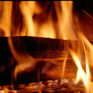 May include: Close-up of a fireplace with burning logs and flames. The flames are orange and yellow, and the logs are brown and black.