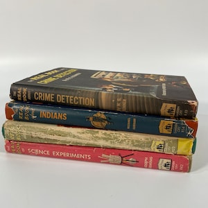 May include: A stack of five vintage paperback books with colorful covers. The titles include "The Real Book About Crime Detection", "The Real Book About Indians", and "The Real Book of Science Experiments".