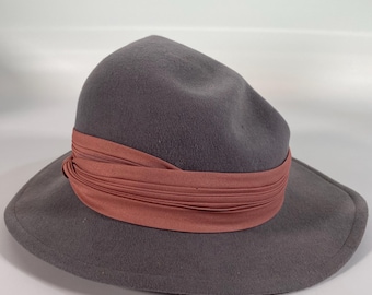 May include: A gray felt fedora hat with a wide brim and a pink ribbon around the crown.