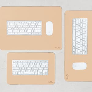 May include: Three beige desk mats with white keyboards and mice. The mats are rectangular and have rounded corners. The top mat has a keyboard and mouse. The bottom mat has a keyboard. The right mat has a keyboard and mouse. The mats have the text "WRL".