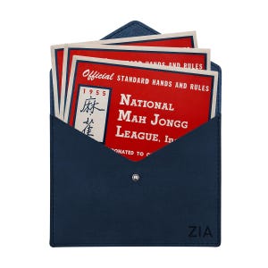 May include: A dark blue envelope-style case with a snap closure and the text ZIA embossed in the corner. Inside are several red cards with white text reading Official Standard Hands and Rules National Mah Jongg League, Inc. 1955.