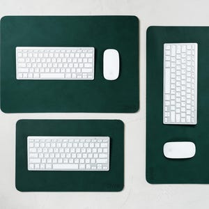 May include: Three dark green rectangular desk pads with rounded corners. Each pad has a white keyboard and a white mouse. The pads vary in size, with the largest at the top and the smallest at the bottom. The brand name "DWB" is visible on each pad.