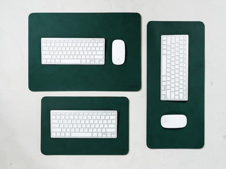 May include: Three dark green rectangular desk pads with rounded corners. Each pad has a white keyboard and a white mouse. The pads vary in size, with the largest at the top and the smallest at the bottom. The brand name "DWB" is visible on each pad.