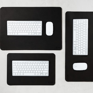 May include: A collection of black desk mats with white keyboards and mice. The mats are rectangular and have rounded corners. The keyboards have a standard layout. The mice are oval-shaped. The mats vary in size.