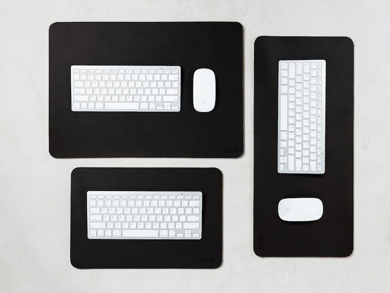 May include: A collection of black desk mats with white keyboards and mice. The mats are rectangular and have rounded corners. The keyboards have a standard layout. The mice are oval-shaped. The mats vary in size.