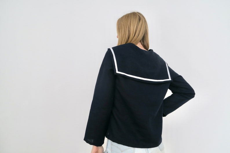 May include: A navy blue long-sleeved sweater with a wide white-trimmed sailor collar.