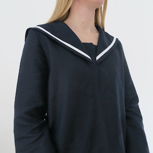May include: A navy blue long-sleeved shirt with a white sailor collar.
