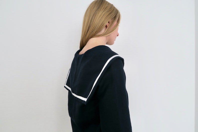 May include: A black sweater with a white sailor collar. The sweater is long-sleeved and has a relaxed fit.