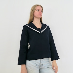 May include: A navy blue long-sleeved shirt with a white sailor collar. The shirt has a relaxed fit and is cropped at the waist.