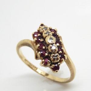 May include: A gold ring with a cluster of red rubies and white diamonds set in a leaf-shaped design.