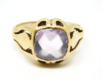 May include: A gold ring with a large, faceted, light purple gemstone set in a decorative, open-work setting.