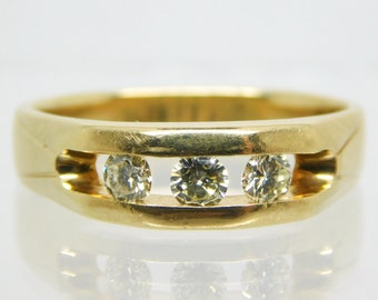 May include: A gold band ring with three round diamonds set in a channel setting.