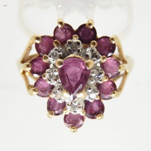 May include: A gold ring with a cluster of pink pear-shaped gemstones and smaller round white gemstones.