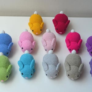 以下が含まれることがあります： ピンク、ブルー、グリーン、パープル、グレー、イエローなど、さまざまな色の、手編みのウサギのぬいぐるみが12個あります。各ウサギは白い尻尾と白い鼻をしています。