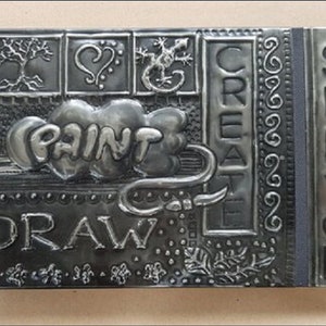 Hardback sketchbook featuring hand embossed pewter patterns and words.